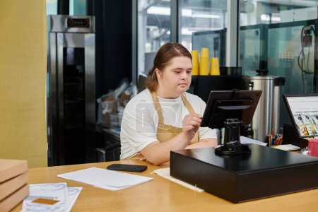 Aufmerksame Mitarbeiterin mit psychischer Störung bedient Geldautomaten, während sie in modernem Café arbeitet
