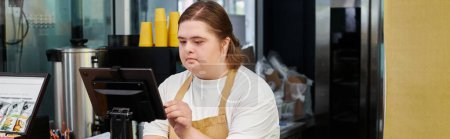 joven empleada con discapacidad mental que opera terminal de efectivo mientras trabaja en la cafetería, pancarta