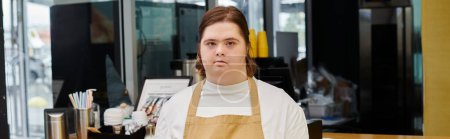 young woman with down syndrome looking at camera while working in modern cafe, horizontal banner
