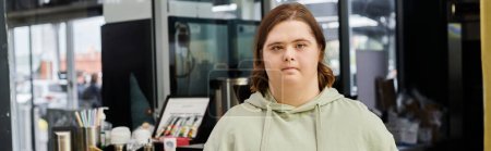young woman with down syndrome looking at camera while working in modern cafe, horizontal banner