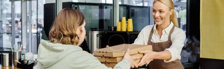administrador de café feliz dando cajas de pizza a cliente femenino con síndrome de Down en la cafetería, pancarta
