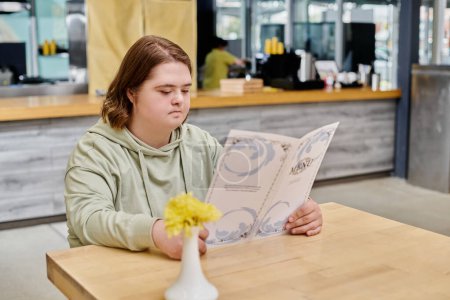 Nachdenkliche Kundin mit Down-Syndrom schaut auf Speisekarte, während sie am Tisch im Café sitzt