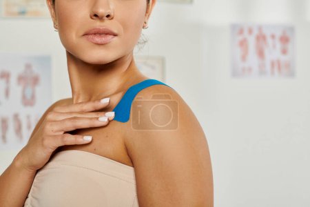 cropped view of attractive young woman with kinesiological tapes on her body during appointment