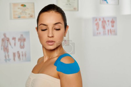 atractiva paciente femenina con cintas cinesiológicas en su cuerpo en la sala médica, atención médica