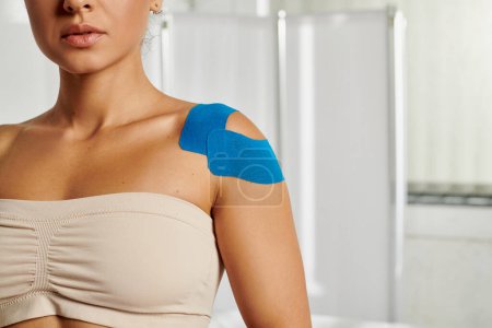 good looking young woman with kinesiological tapes on her shoulder during appointment, healthcare
