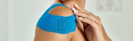 Photo for Young woman with kinesiological tapes on her shoulder during her doctor appointment, banner - Royalty Free Image