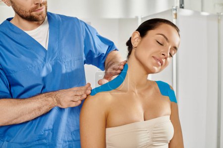 doctor barbudo poniendo cintas kinesiológicas en el hombro de su hermoso paciente, cuidado de la salud