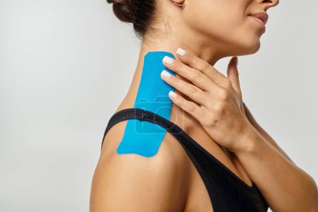 Ausschnitt einer jungen Frau, die im Profil posiert, mit kinesiologischen Klebebändern am Hals und an der Schulter