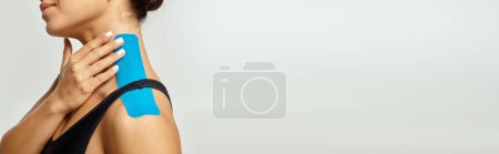 Foto de Vista recortada de la mujer posando de perfil con cintas kinesiológicas en el cuello y el hombro, pancarta - Imagen libre de derechos