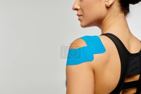 Photo for Cropped view of young woman in black sport outfit posing with kinesiological tape on her shoulder - Royalty Free Image