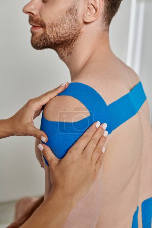 Photo for Cropped view of female doctor putting kinesio tapes on body of smiling patient, healthcare - Royalty Free Image
