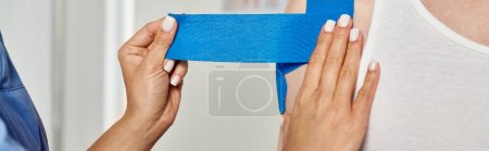 Foto de Vista recortada de la mano de la doctora poniendo cintas de kinesio en su paciente masculino, cuidado de la salud, bandera - Imagen libre de derechos