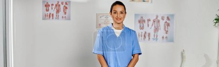 Photo for Joyous attractive young doctor in medical costume posing in her office and smiling at camera, banner - Royalty Free Image