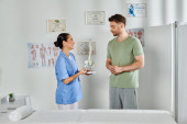 cheerful doctor showing spine model to her handsome patient during appointment, healthcare puzzle #684736296