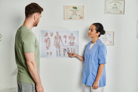 Téléchargez les photos : Médecin joliment attrayant montrant des schémas d'anatomie à son patient pendant le rendez-vous, soins de santé - en image libre de droit