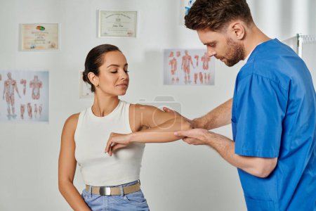 handsome doctor with beard checking elbow of his young patient during appointment, healthcare