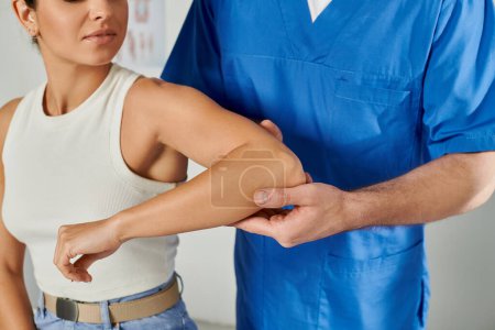 Photo for Cropped view of doctor in medical costume checking elbow of his young female patient, healthcare - Royalty Free Image