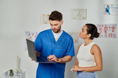 Foto de Mujer atractiva paciente mirando a su médico barbudo con portátil en sus manos, atención médica - Imagen libre de derechos