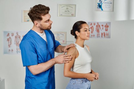 Photo for Handsome doctor in blue medical costume checking muscles of his young female patient, healthcare - Royalty Free Image