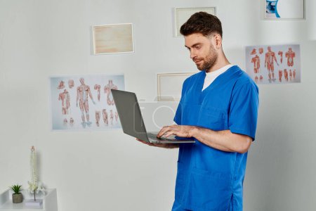 gut aussehender bärtiger Arzt schaut auf seinen Laptop, während er in seinem Büro hart arbeitet, Gesundheitswesen