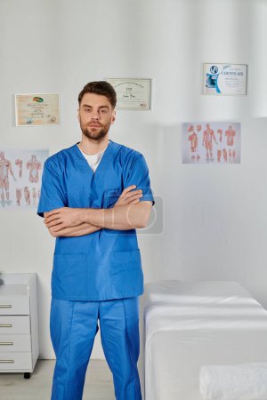 good looking bearded doctor posing with arms crossed on chest and looking at camera, healthcare