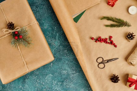 decorated gift boxes near craft paper with pine decor and scissors on blue textured backdrop