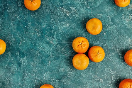 Draufsicht auf frische und reife Mandarinen auf blau strukturierter Oberfläche, weihnachtlicher Stillleben-Hintergrund