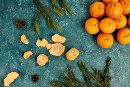 fresh mandarins and pine cones with fir branches on blue rustic backdrop, Christmas theme, top view