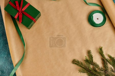 caja de regalo verde con lazo rojo cerca de la rama de pino y cinta en papel de regalo artesanal, decoración de Navidad
