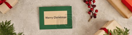 greeting card with Merry Christmas lettering near gift boxes and holly berries, horizontal banner