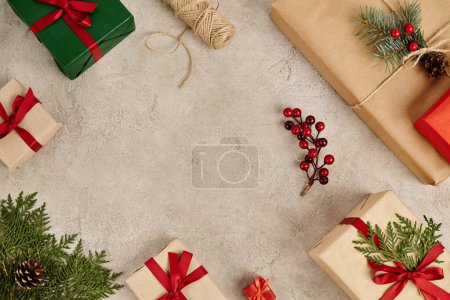 Foto de Fondo de Navidad, regalos con cintas rojas y decoración de pino con bayas de acebo en superficie texturizada - Imagen libre de derechos