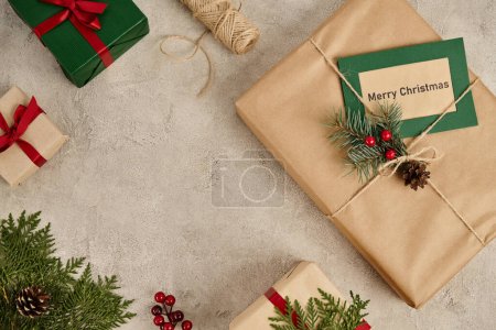 Téléchargez les photos : Joyeux Noël carte de voeux près de boîtes-cadeaux décorées sur fond gris texturé, thème de fête - en image libre de droit