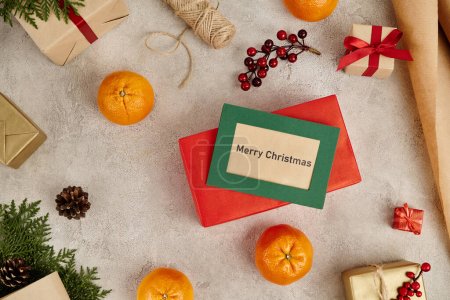 Frohe Weihnachten Grußkarte in der Nähe von Mandarinen und verzierte Geschenke auf grau strukturiertem Hintergrund
