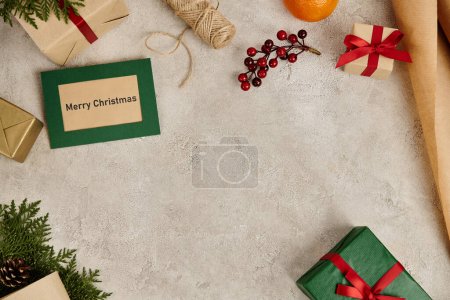 Christmas backdrop with decorated gift box and greeting card on textured surface with empty space