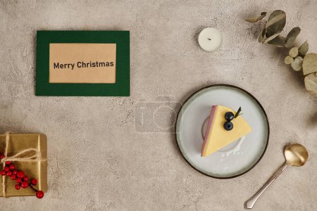Merry Christmas greeting card near traditional pudding and gift box on grey textured backdrop