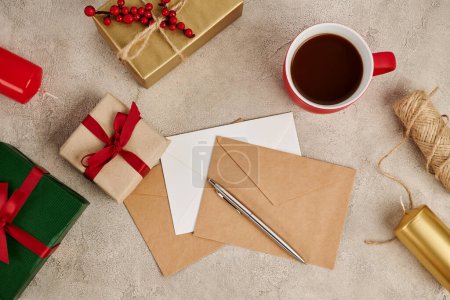 Téléchargez les photos : Chocolat chaud traditionnel près des enveloppes et des boîtes-cadeaux avec des bougies sur la texture grise, Noël - en image libre de droit