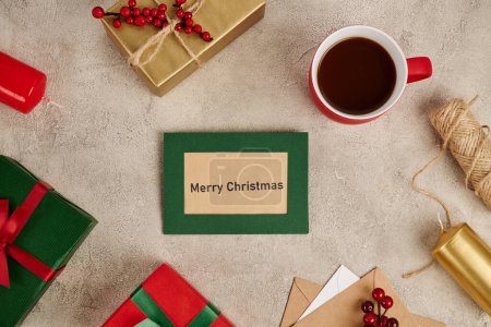 Merry Christmas greeting card near decorated gift boxes and mug of hot chocolate on textured surface