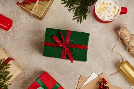 green gift box in frame with colorful Christmas presents and hot chocolate with marshmallow