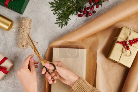 cropped view of woman with scissors cutting twine near gift box and craft paper, diy Christmas gifts