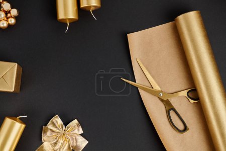 Schere und Papier neben dekorativen Schleifen und Kerzen, goldene und glänzende Weihnachtsgegenstände auf schwarz