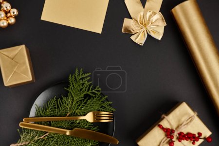 goldenes Besteck auf Wacholderzweigen neben glänzendem Weihnachtsdekor auf schwarzem Hintergrund, Exklusivität