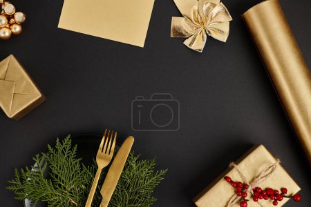 goldenes Besteck auf Wacholderzweigen in der Nähe von glänzendem Weihnachtsdekor auf schwarzem Hintergrund, festlicher Rahmen