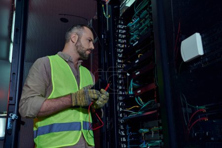 attractive focused man in safety vest and gloves with detector in hands working hard, data center