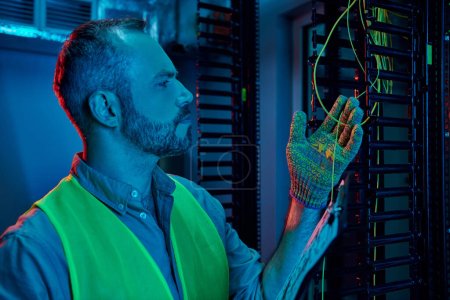 Photo for Good looking pensive technician in safety clothes working in data center with cables and wires - Royalty Free Image