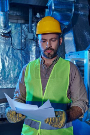 Photo for Good looking dedicated professional in helmet looking attentively at his notes, data center - Royalty Free Image