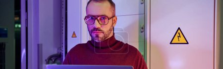 Photo for Devoted specialist with glasses holding his laptop and looking at camera, data center, banner - Royalty Free Image
