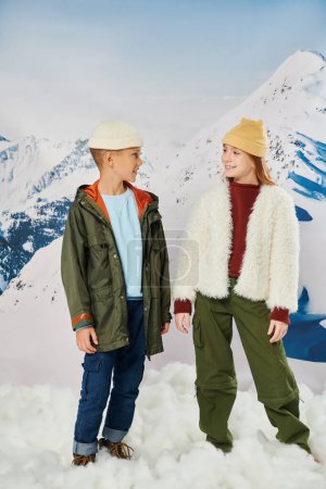 vertical shot of preadolescent boy and girl in winter attire smiling at each other, fashion concept