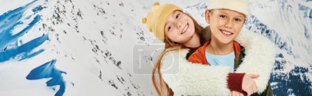 little friends in warm attire hugging and posing with mountain background, fashion concept, banner