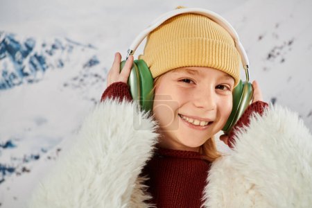 portrait of joyous little girl touching her headset and smiling joyfully at camera, fashion concept