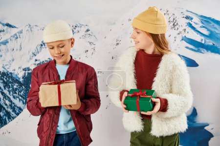 fröhliche Preteen Mädchen mit Mütze schaut ihre Freundin an, hält Geschenke in den Händen, Modekonzept